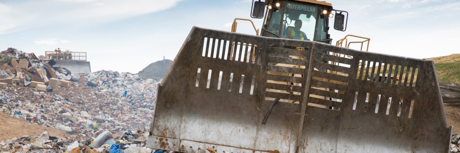A waste management professional operating a bulldozer in a landfill.